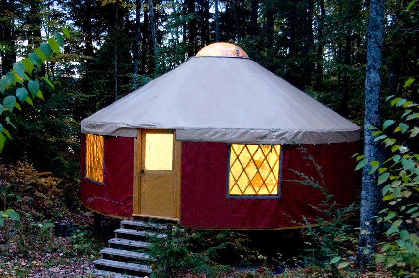 A 24 foot yurt glowing at dusk with lights inside