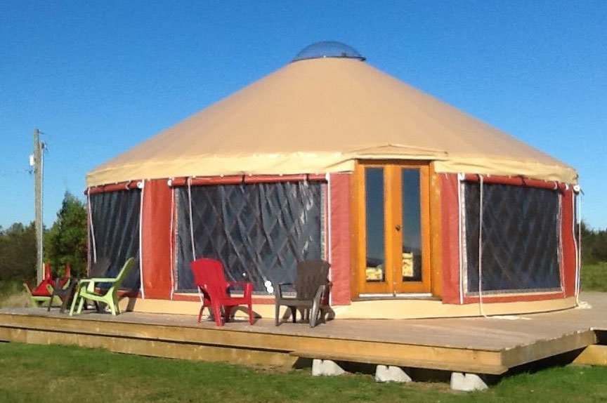 A 30 foot yurt with roll-up walls on a wooden deck
